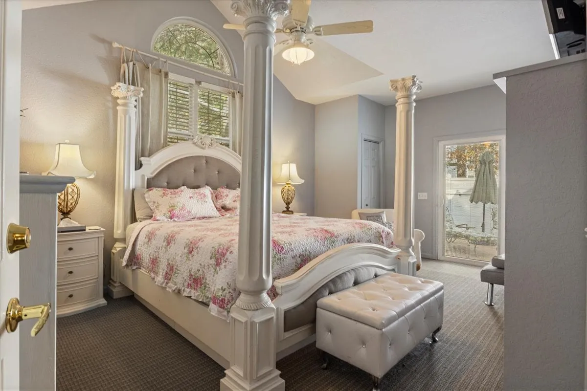 A beautifully appointed king suite featuring an ornate bed frame with floral bedding, flanked by decorative lamps, a window flooding the room with natural light, and a stylish ottoman at the foot of the bed. The space exudes serenity and warmth, perfect for private relaxation.