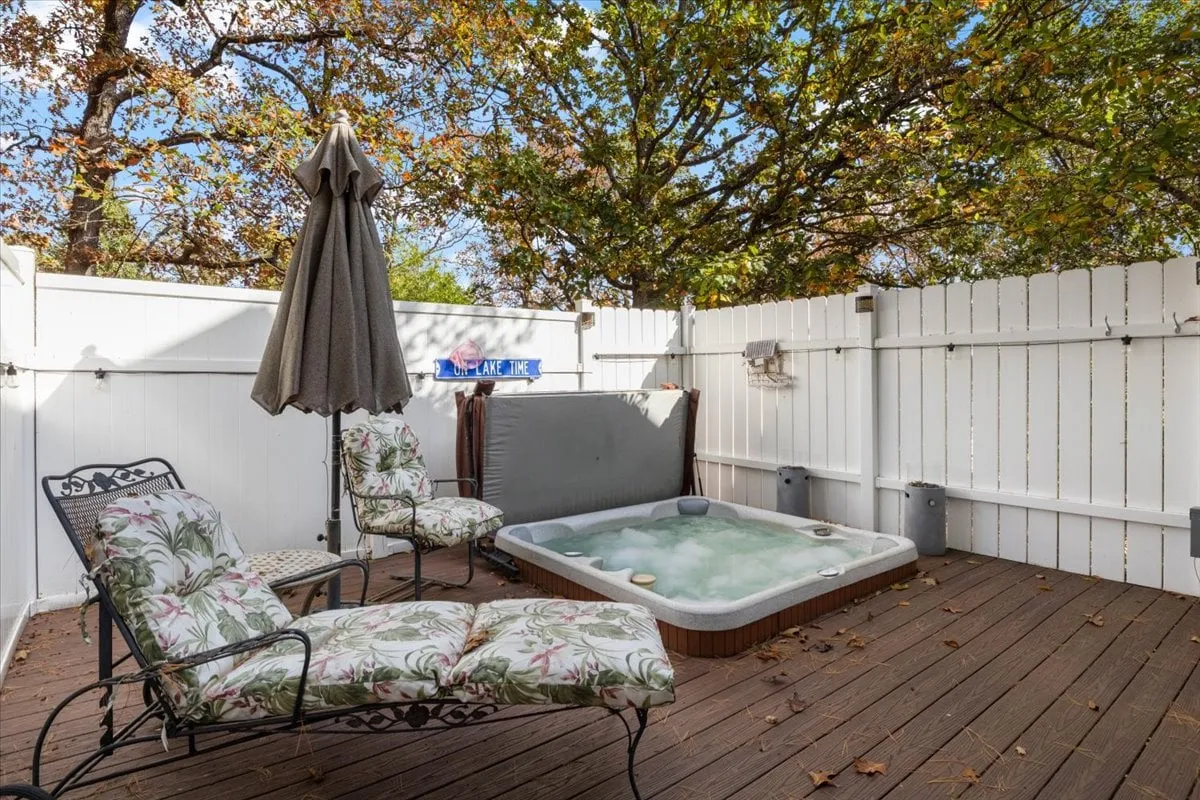 An inviting outdoor scene featuring a bubbling hot tub, lounge chairs, and a large umbrella, all set in a serene, natural environment. The setup is ideal for both daytime relaxation and evening stargazing.
