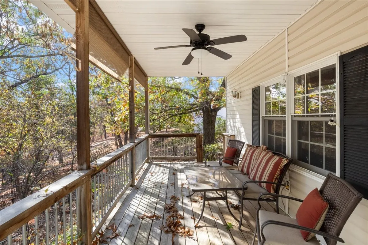 A charming porch swing adorned with striped cushions overlooks a serene landscape of trees, offering a cozy spot to relax, read, or socialize. The scene is bathed in soft natural light, emphasizing a peaceful atmosphere ideal for enjoying sunrises or evening stargazing.