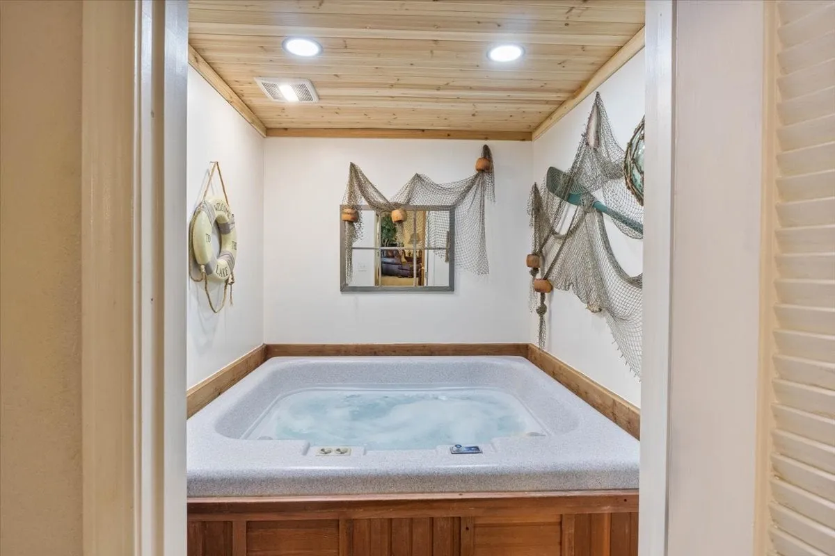 A tranquil indoor hot tub scene with decorative fishing net, warm wooden paneling, subtle nautical décor, and a mirror reflecting the soft lighting. The ambiance exudes relaxation and comfort, perfect for unwinding after a day on the lake.