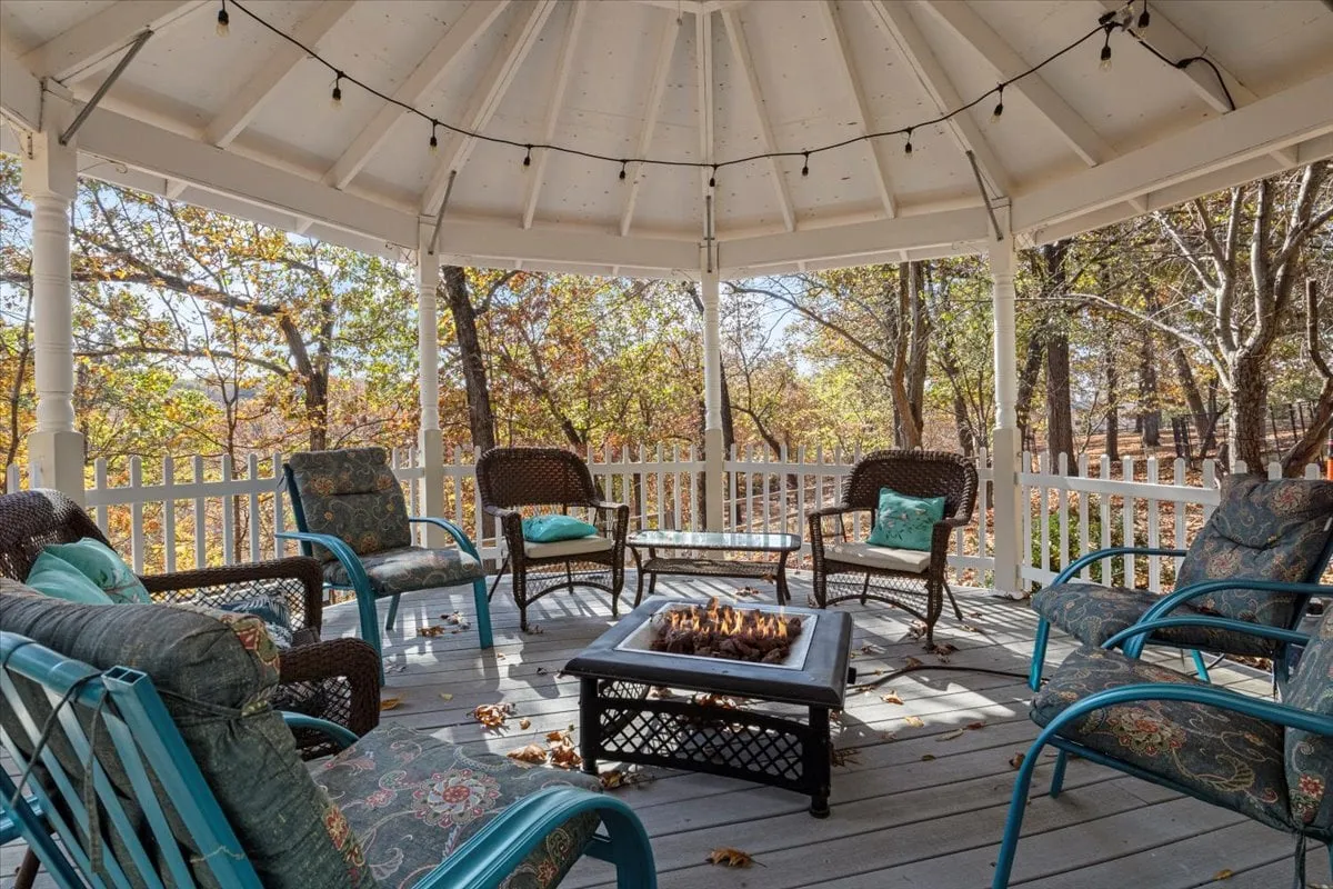 An inviting fire pit sits surrounded by comfortable seating and tall trees, creating a cozy area for gatherings. The setting is ideal for enjoying warm drinks, evening bonfires, or sharing stories under the stars after a day on the lake.