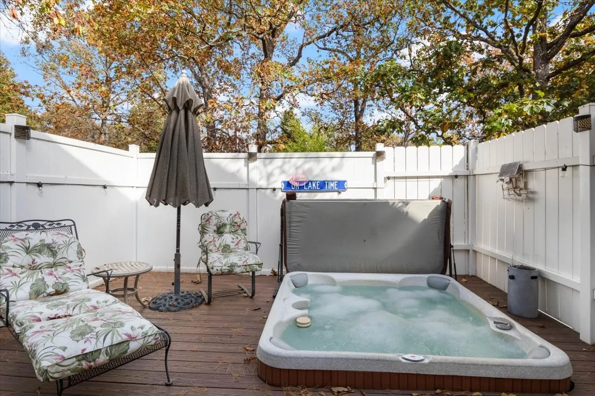 The image showcases an inviting hot tub surrounded by plush lounge chairs and a sun umbrella, set against a tranquil wooded backdrop. The scene is bathed in the warm glow of sunset, hinting at relaxation, socializing, and the opportunity to connect with nature. The setting conveys privacy and luxury, perfect for unwinding or gathering with friends and family.