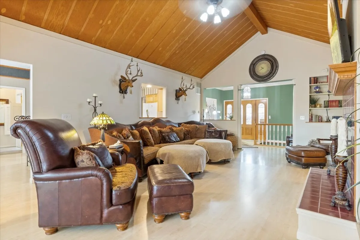 A spacious, inviting living area featuring a large sectional sofa, antler wall decor, wooden ceiling, and a television. The room exudes warmth and comfort, ideal for family gatherings or cozying up for a movie night.