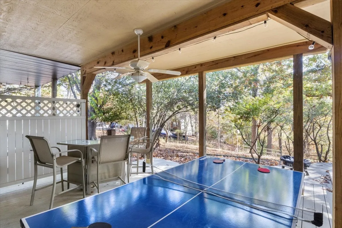 This exterior image features a ping pong table surrounded by outdoor seating and lush greenery, capturing a relaxed and playful mood. The scene is set up for friendly competitions or group socialization, with the table and chairs inviting guests to enjoy games or meals outside.